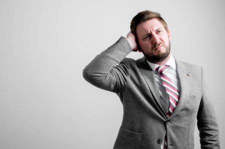 Portrait of business man wearing business clothes gesturing head ache isolated on grey background...