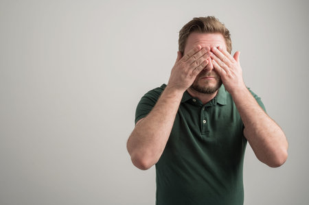 Portrait of serious stylish attractive man with thick beard, dressed in casual green t shirt...