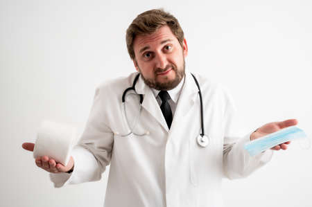 Portrait of male doctor with stethoscope in medical uniform showing toilet paper and protective mask posing on a white isolated backgroundの写真素材