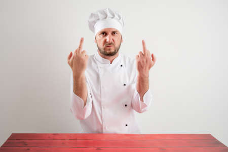 Young male chef in white uniform showing double fuck you posing on a white isolated backgroundの写真素材