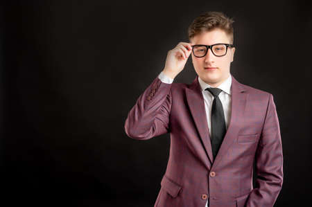 Portrait of law student with blond hair wearing glasses dressed in burgundy jacket, white shirt and black tie posing on isolated background with copy space advertising areaの写真素材