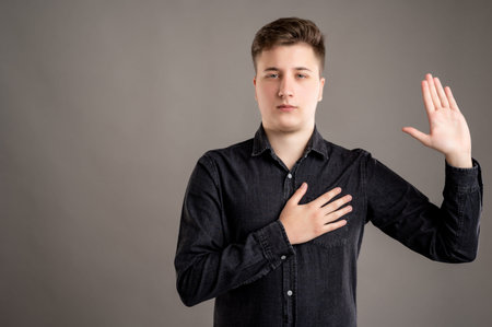 Portrait of serious stylish attractive man dressed with a casual black shirt taking oath gesture...