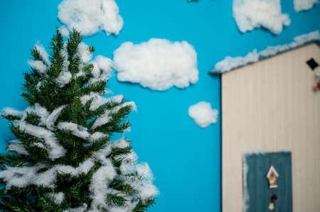 Decorative Christmas studio with a house with blue door, wooden bench and skis,  fake clouds and snowの写真素材
