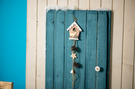 Decorative Christmas studio with a house with blue door, wooden bench and skis, snowman, fake clouds and snowの写真素材