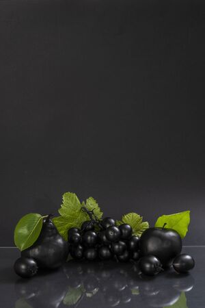 Conceptual image of black fruits on gray reflective surfaceの写真素材