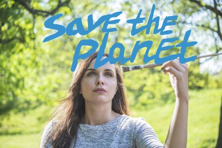 A young woman with a brush paining Save the planet message (blue)の写真素材