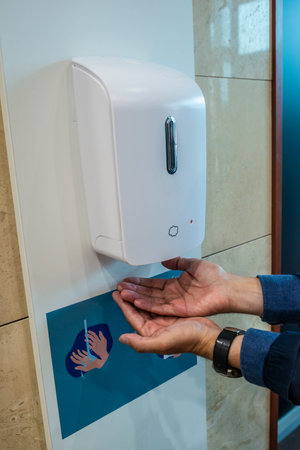 People entering a shopping mall and disinfecting their hands to prevent against corona virus
