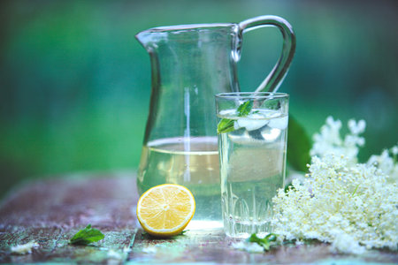 Fresh cool home elderberry lemon lemonade jug and glass on a table in the garden
