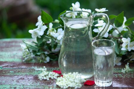 Fresh cool home elderberry lemon lemonade jug and glass on a table in the gardenの写真素材