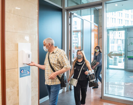 Sofia, Bulgaria - May 18 2020: People entering a shopping mall and disinfecting their hands to...