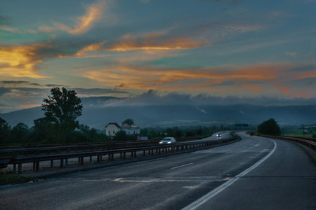 A highway road at dusk with blurred cars in motion after heavy rain