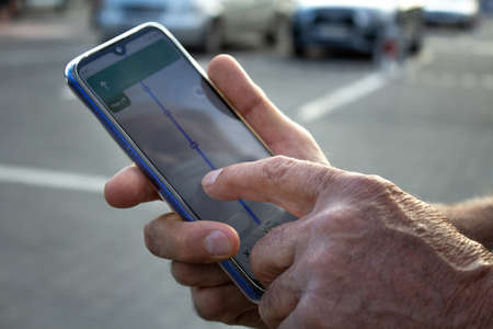 An elder person using a smartphone to navigate in the cityの写真素材