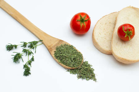 Dried savory in wooden spoon decorated with ripe tomatoes,bread and fresh savory stemsの写真素材