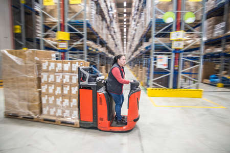 A worker operating forklift machine in a huge warehouce centerのeditorial素材