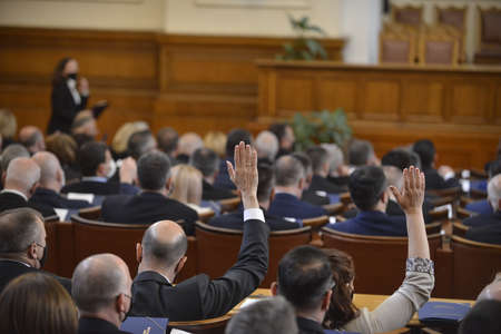 Sofia, Bulgaria - Apr 15 2021: National Assembly members raising hands during the first sitting after the elections. View from behind.のeditorial素材