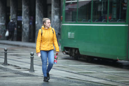 Sofia, Bulgaria - Apr 4 2021: A girl with an umbrella and smartphone is walking on the streetのeditorial素材