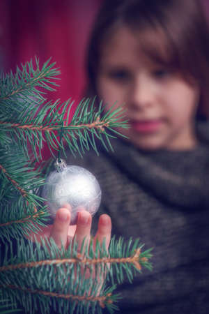 Close up of young girl decorating Christmas tree - background blurの写真素材