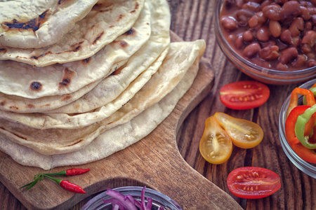 Mexican corn tortilla tacos with vegetables on wooden background