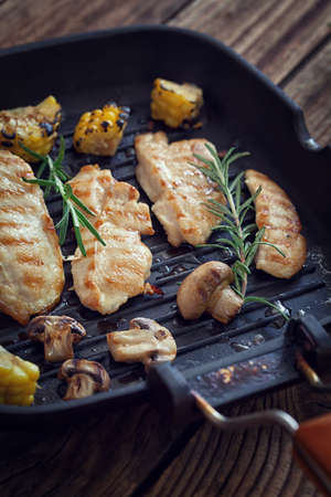 Grilled chicken with mushroom and rosemary on a iron skillet or grill panの写真素材