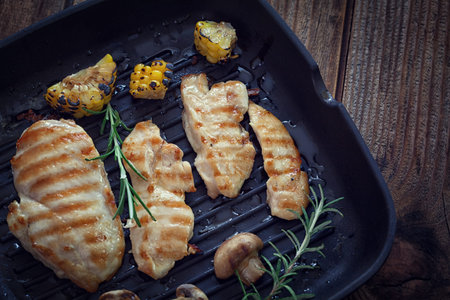 Grilled chicken breast with mushroom and rosemary on a wooden board or grill panの写真素材