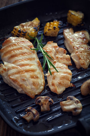 Grilled chicken breast with mushroom and rosemary on a wooden board or grill panの写真素材