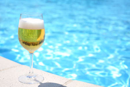 Glass of beer at the swimming poolの写真素材