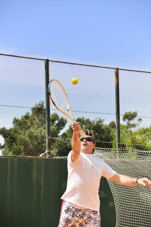 Middle age man playing tennisの写真素材