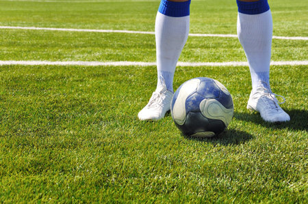 Human leg and soccer ball on the grass fieldの写真素材