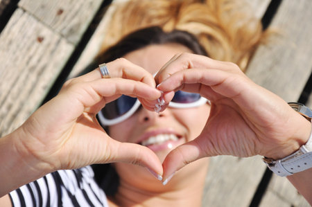 Attractive woman lying and showing heartの写真素材