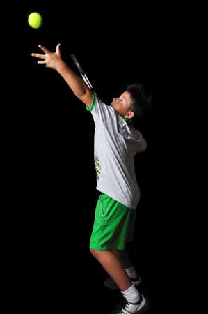 Tennis boy serving isolated in blackの写真素材
