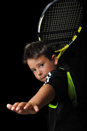 Tennis boy playing forehand isolated in blackの写真素材