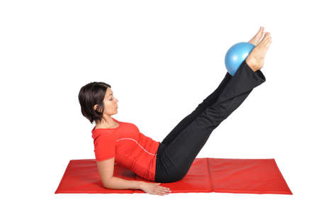 Fit young female pilates instructor showing different exercises with ball on a white background の写真素材