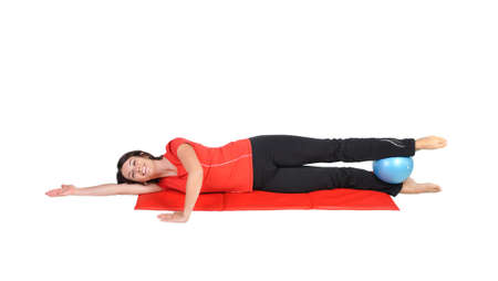 Fit young female pilates instructor showing different exercises with ball on a white background の写真素材
