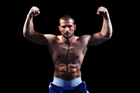 Powerful muscular boxer posing on black background