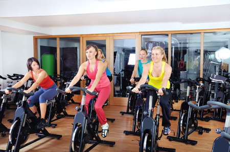 Beautiful women doing exercise in a spinning class at gymの写真素材