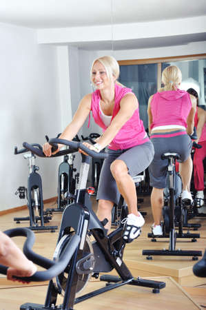 Beautiful women doing exercise in a spinning class at gymの写真素材