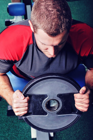 Muscular man with weight exercising in a gym