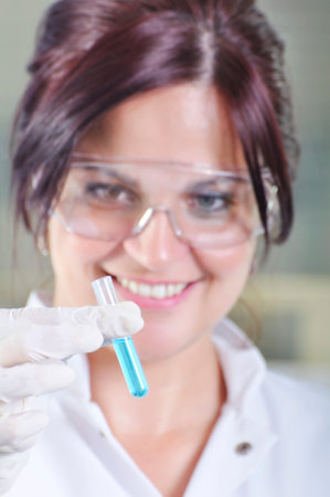 Attractive young PhD student scientist observing the blue indicator color shift after the solution...