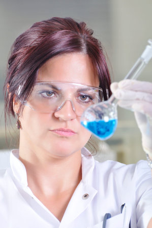 Attractive young PhD student scientist observing the blue indicator color shift after the solution...