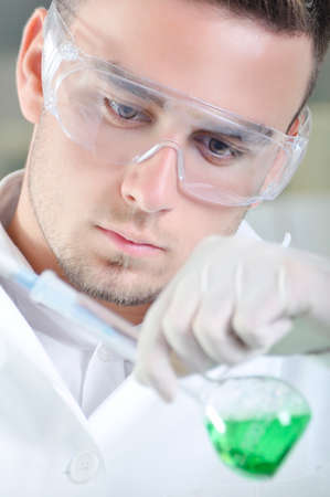 Attractive young PhD student scientist observing the green indicator color shift after the solution destillation in chemical laboratoryの写真素材