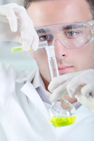 Attractive young PhD student scientist observing the yellow indicator color shift after the solution destillation in chemical laboratoryの写真素材