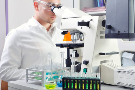 Young scientist studying new substance or virus in microscope
