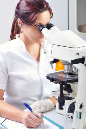 Young scientist studying new substance or virus in microscopeの写真素材