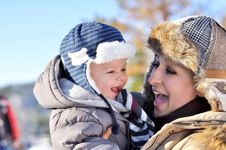 Happy family. Young mother in a winter park with her sweet baby boyの写真素材
