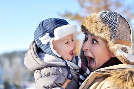 Happy family. Young mother in a winter park with her sweet baby boyの写真素材