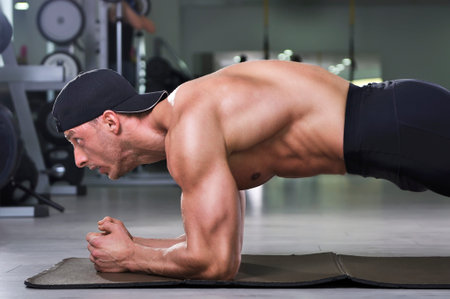 Handsome powerful athletic man doing plank exercise. Strong bodybuilder with  perfect muscular abs,...