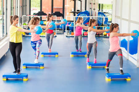 Group of beautiful young women working out on blue stepper and smiling.の写真素材