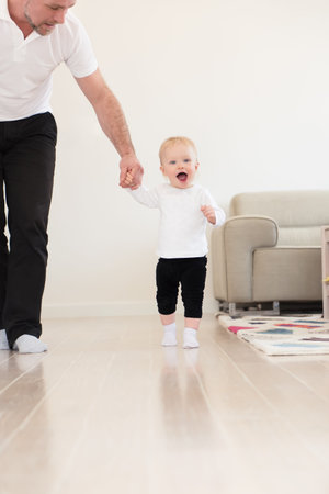 Happy family enjoying at home. Father and his beautiful baby girl playing and learning how to walk....