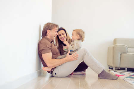 Happy family sitting on floor with their little baby. Family spending time at home with their son.の写真素材