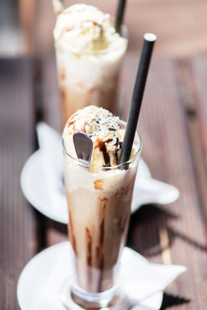 Ice coffee on a wood table with cream being poured into it showing the texture and refreshing look...